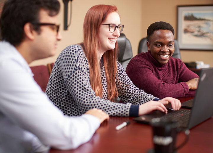 Woman typing on laptop with others next to her